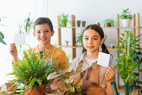Preteen kids holding sticky notes near plants at home