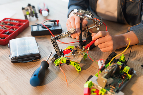 Cropped view of boy making robotic model with millimeter near screwdriver at home