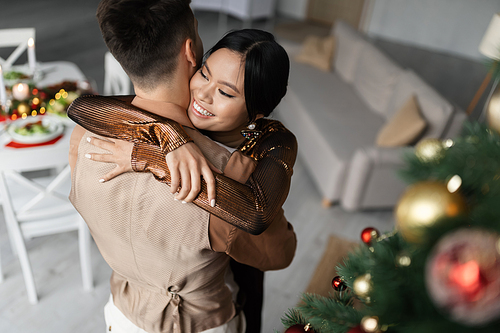 high angle view of cheerful asian woman hugging husband during Christmas celebration