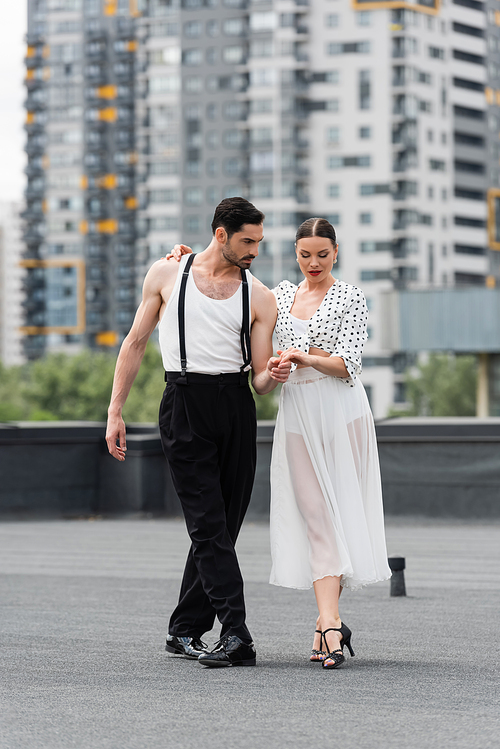 Professional dancers holding hands of roof of building outdoors