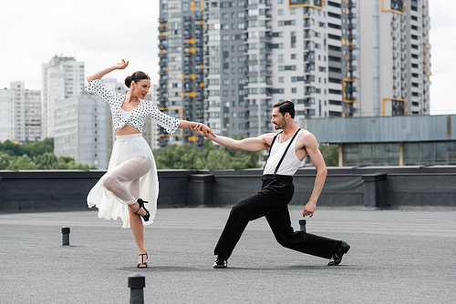 Side view of smiling dancers moving on roof of building outdoors