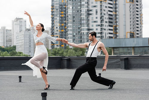 Stylish dancers moving on roof of building at daytime