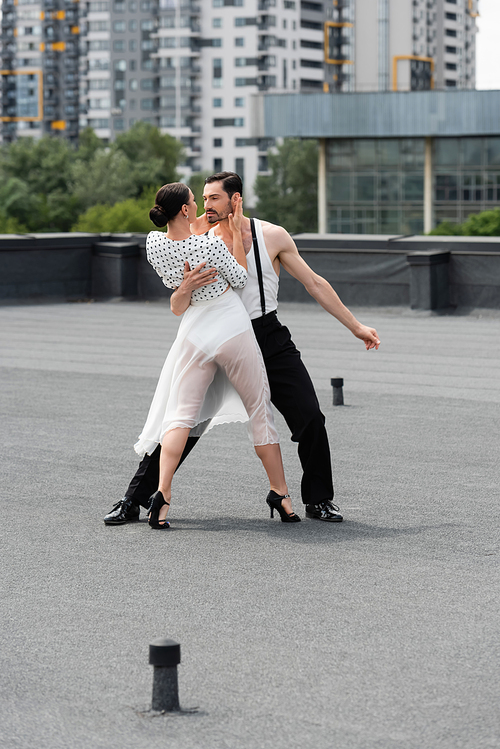 Professional ballroom dancers performing choreography on rooftop of building outdoors