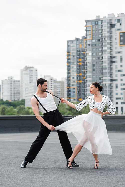 Side view of stylish dancer in heels dancing with partner on roof