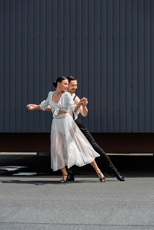 Smiling dancers performing choreography on roof at daytime