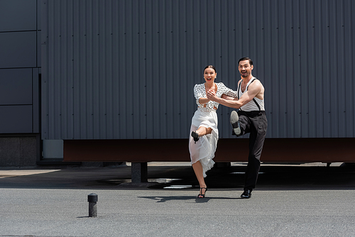 Positive dancers looking away while performing choreography on rooftop