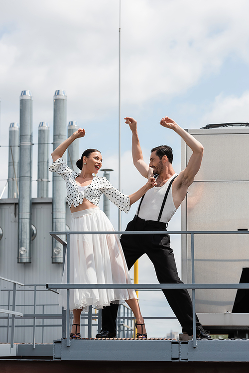 Positive and stylish professional dancers moving on rooftop of building outdoors