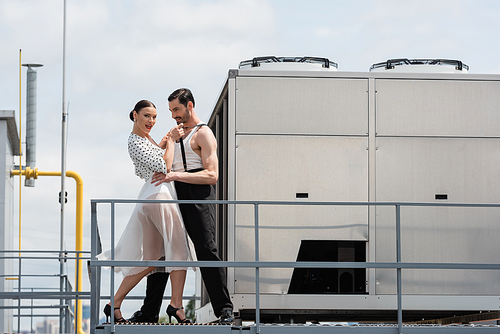 Stylish professional dancer in heels looking at camera while moving with partner on roof