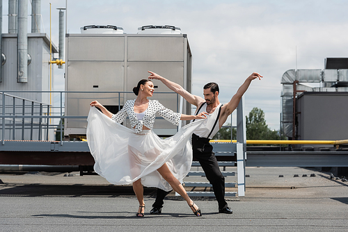 Positive and stylish dancers performing choreography on roof