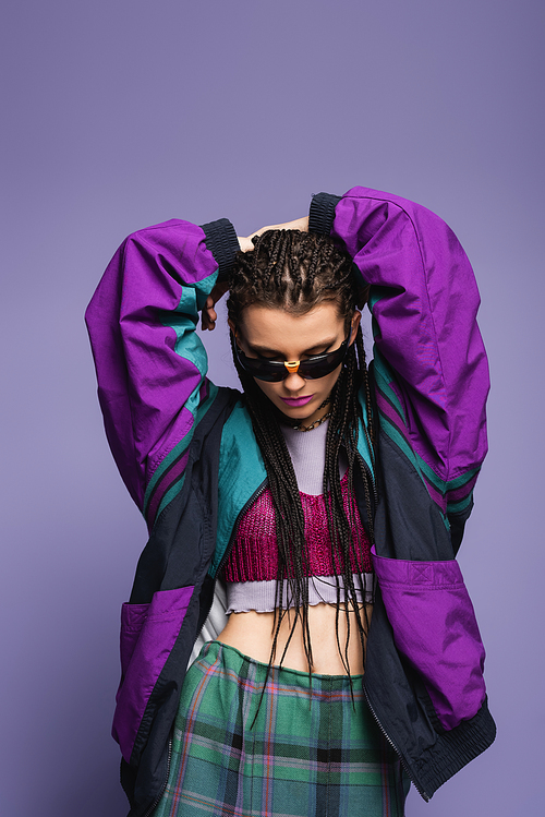 Fashionable model with braids hairstyle and retro sports jacket posing isolated on purple