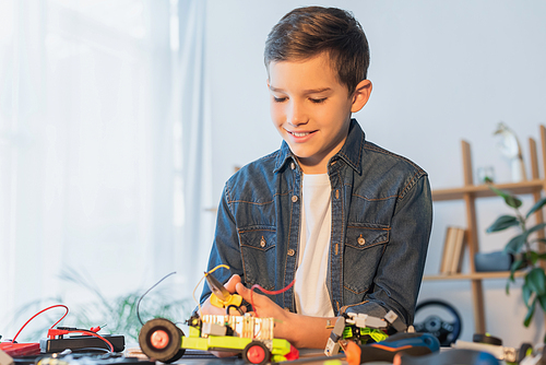 preteen boy with pliers assembling robotics model on table at home