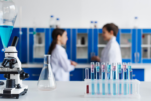 selective focus of test tubes and microscope near children on blurred background in chemical lab