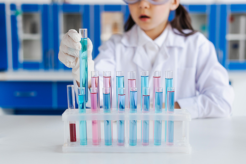 cropped view of blurred girl in latex glove holding test tube in laboratory