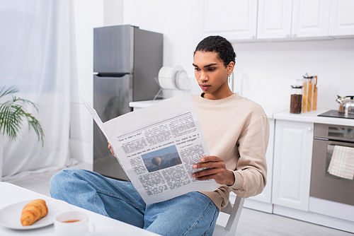 african american man reading newspaper near breakfast on table