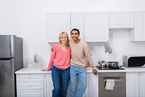 happy multiethnic couple standing in modern kitchen