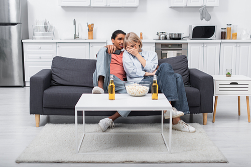 young interracial couple watching scary movie in living room