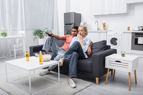 scared interracial couple watching movie in living room