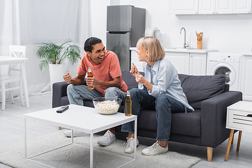 excited multiethnic couple cheering while watching sport match in living room