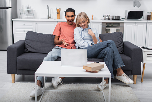 happy multiethnic couple smiling during video call on laptop