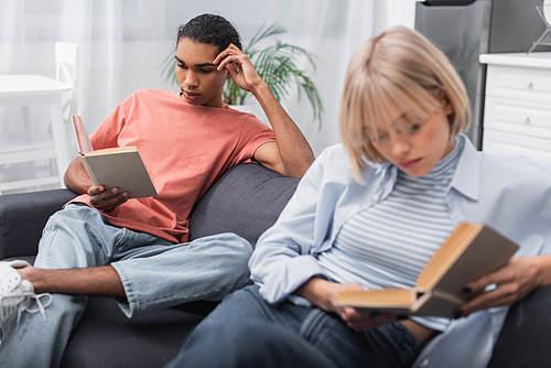 young african american man and blonde woman reading books