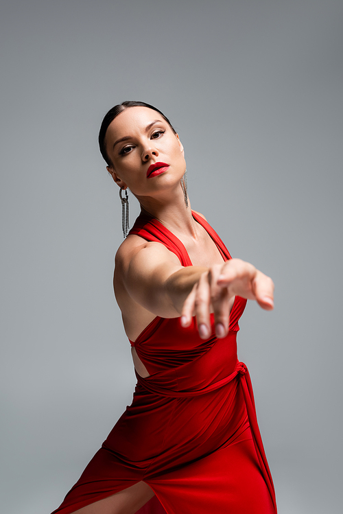 Dancer in red dress pointing with finger at camera isolated on grey