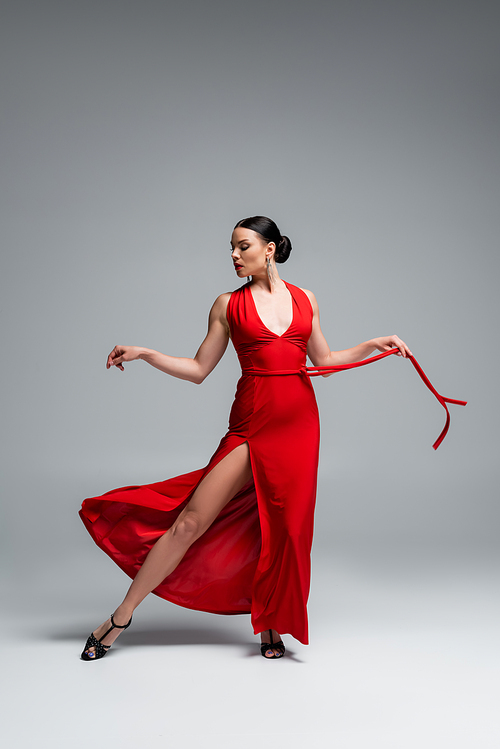 Stylish ballroom dancer performing tango on grey background