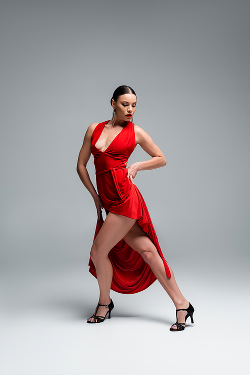 Professional dancer in heels performing tango choreography on grey background