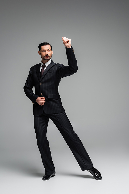 Full length of stylish ballroom dancer moving on grey background