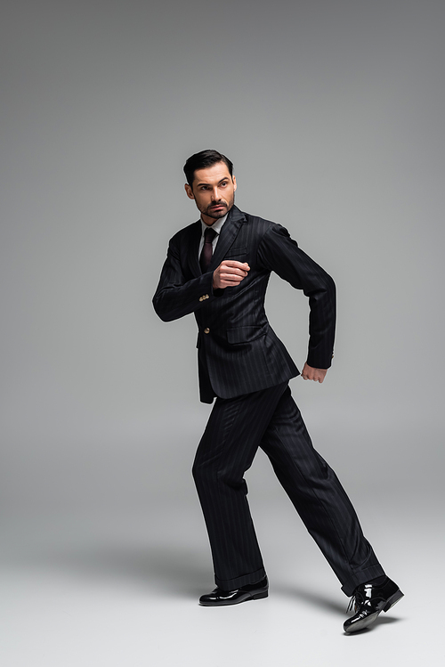 Full length of elegant ballroom dancer moving on grey background