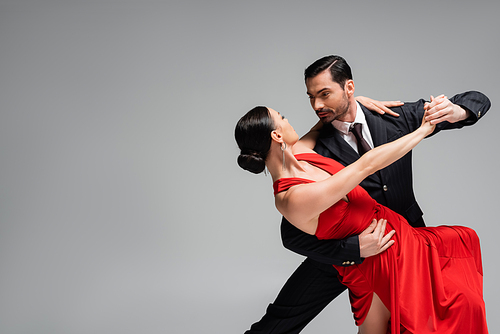 Elegant man in suit dancing tango with partner isolated on grey