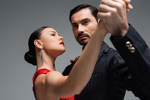 Professional ballroom dancers holding hands isolated on grey