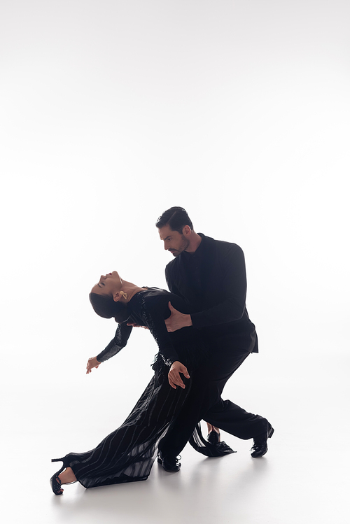 Couple in suit and dress performing tango on white background