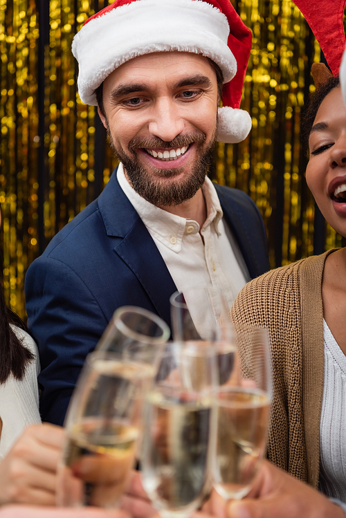 Smiling businessman in santa hat clinking champagne with multiethnic business people