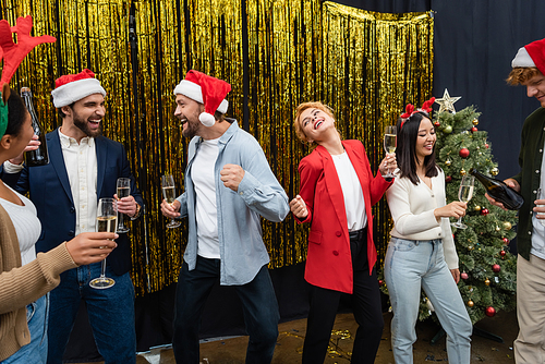 Multiethnic business people with champagne dancing during Christmas celebration in office