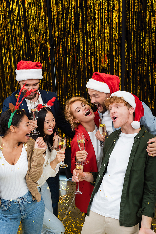 High angle view of excited multiethnic business people with champagne dancing near tinsel in office
