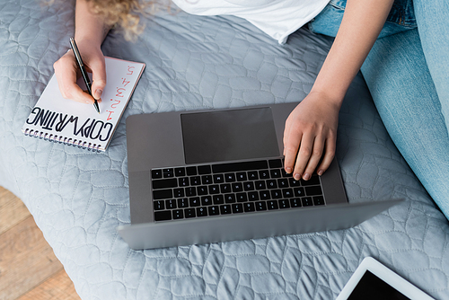 top view of cropped woman near laptop and notebook with copywriting lettering