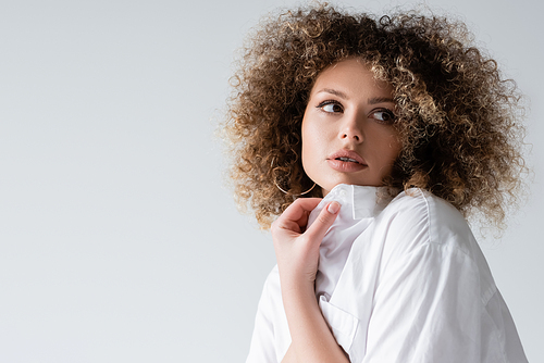 Portrait of curly woman in blouse looking away isolated on white