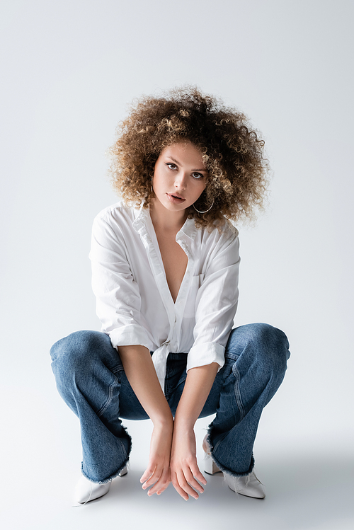 Fashionable woman in blouse and jeans posing on white background