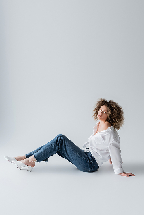 Stylish woman sitting on white background