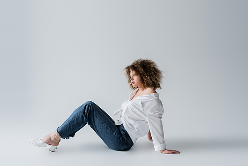 Stylish model in jeans sitting on white background