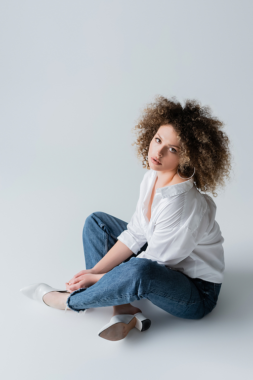 High angle view of stylish young woman sitting on white background