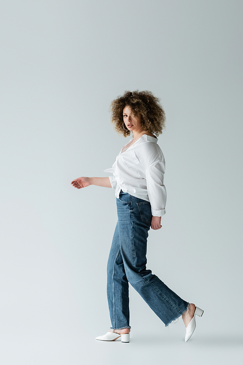 Fashionable woman walking and looking at camera on white background