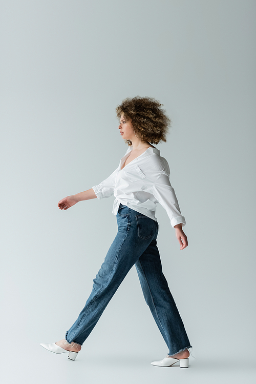 Side view of stylish woman walking on white background
