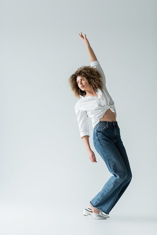 Pretty woman in jeans and blouse posing on white background