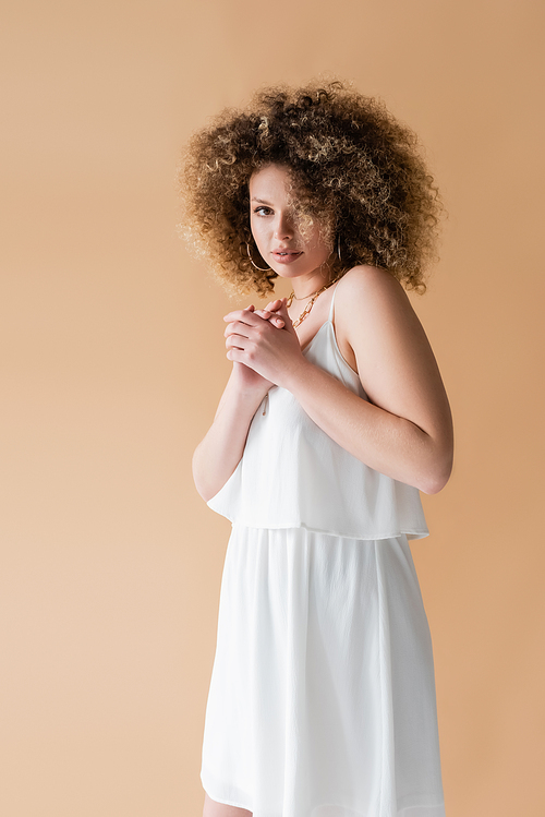 Portrait of curly model in white clothes isolated on beige