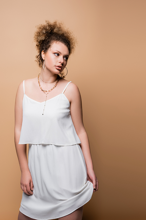 Stylish woman touching white skirt on beige background