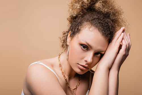 Portrait of pretty young woman in accessories posing isolated on beige