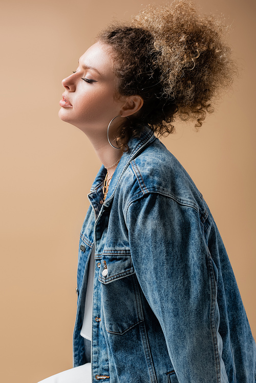 Young model in denim jacket and accessories isolated on beige