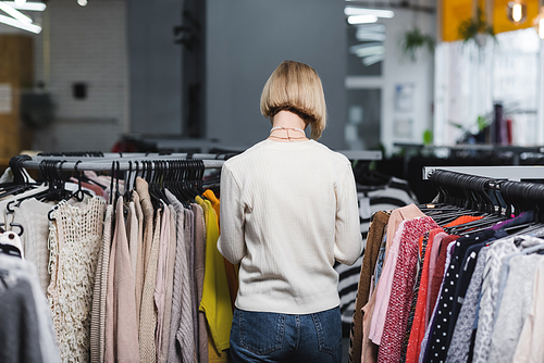 Back view of woman standing near clothes in vintage shop