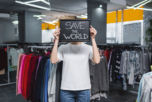 Retailer holding board with save the world lettering in second hand